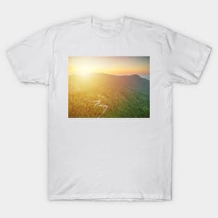 Aerial view of curvy mountain road through a jungle ay sunset T-Shirt